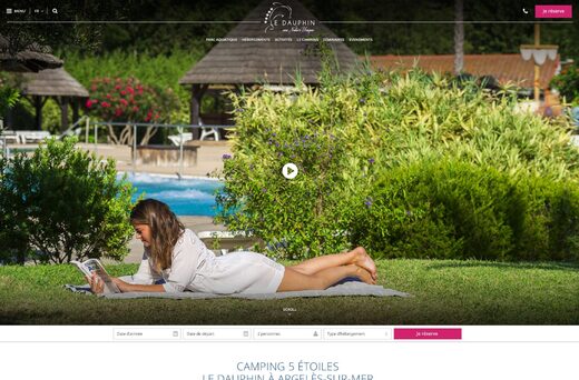 Femme lisant près piscine, entourée de verdure et parasols, bouton "Réserver" et logo Le Dauphin.