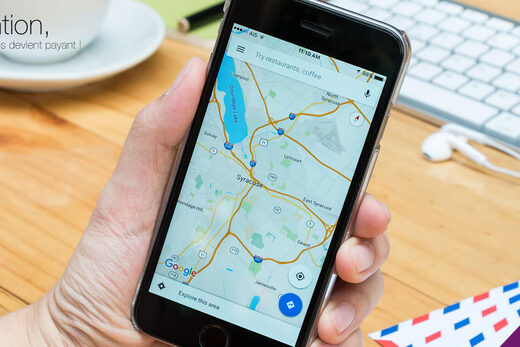 Smartphone avec Google Maps, bureau organisé, notification sur service payant.