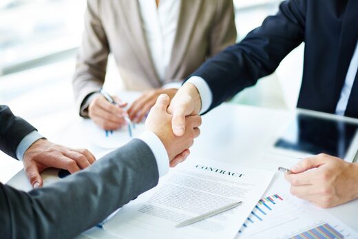 Professionnels concluant un partenariat autour de documents et graphiques, dans un cadre d'expertise digitale.
